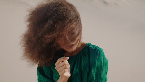 model girl posing sand desert in black dress close up. portrait curly woman.