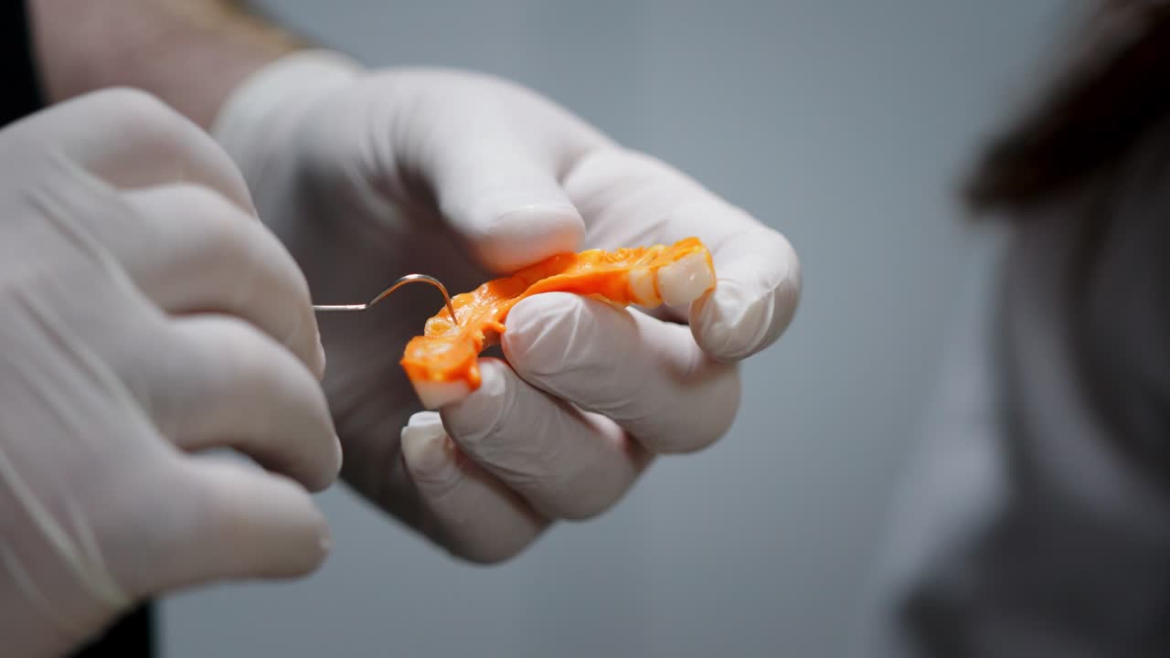 manos de un dentista con guantes médicos trabajando con implantes dentales y coronas en un consultorio médico