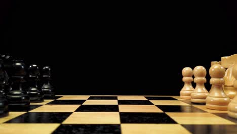 dolly shot forward along chess pieces standing on either side of a chessboard against a black background