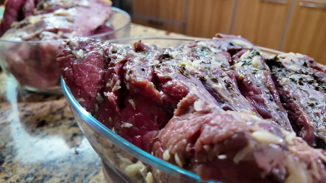 Carne cruda marinata in ciotola di vetro che ruota in cucina domestica