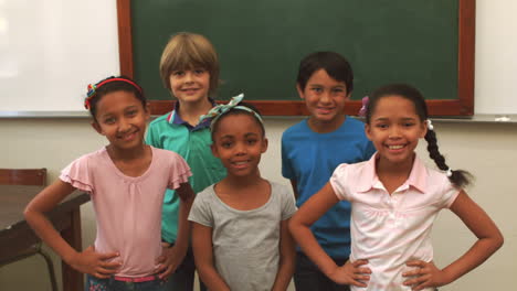 cute pupils smiling at camera in classroom