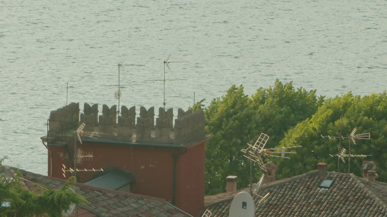 슬로우 모션 샷, 이탈리아 말세시네(malcesine)의 옥상 위로 날아다니는 새, 배경에는 라고 디 가르다(lago di garda)