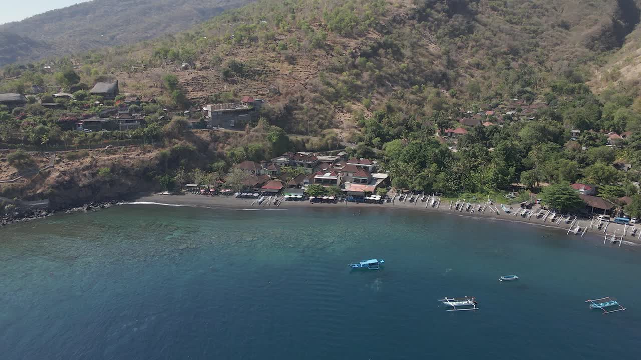 las laderas secas de las montañas inclinan hacia la pintoresca playa de jemeluk en bali