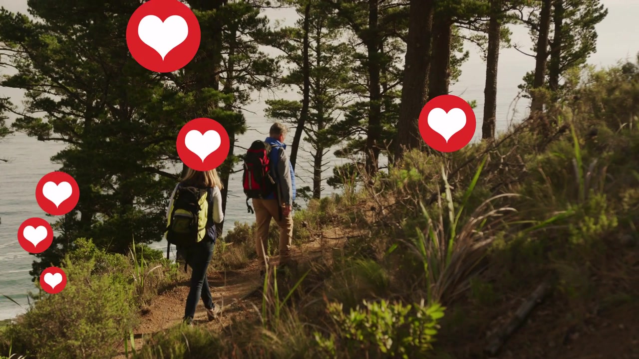 Due escursionisti che camminano su un sentiero costiero, con icone a forma di cuore rosso che si moltiplicano sopra i loro zaini, per il viaggio.