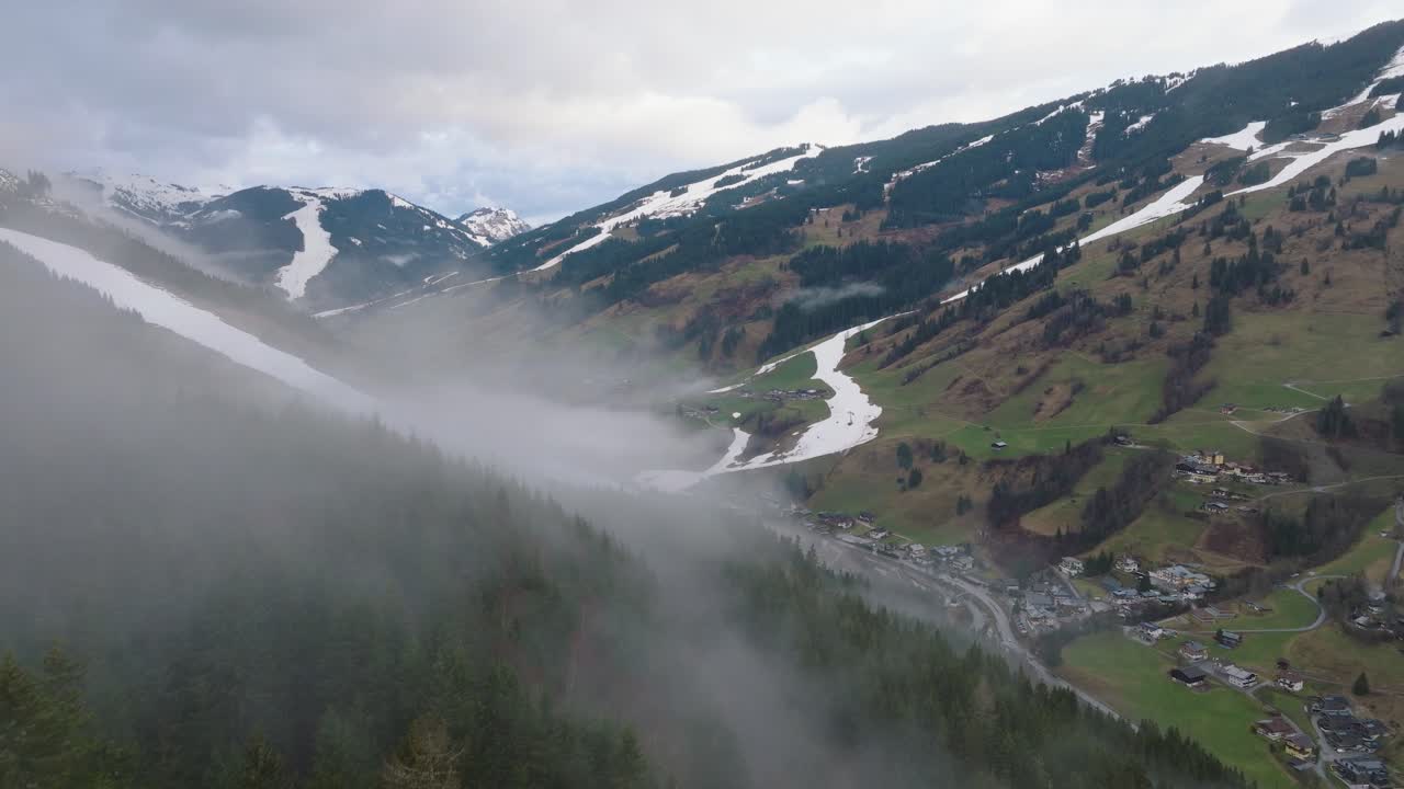 saalbach-hinterglemm con niebla sobre las montañas y el pueblo al anochecer, vista aérea