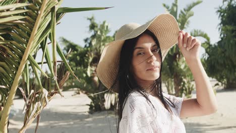 retrato de una feliz mujer hispana con sombrero de sol y vestido de sol sonriendo en una playa soleada, cámara lenta