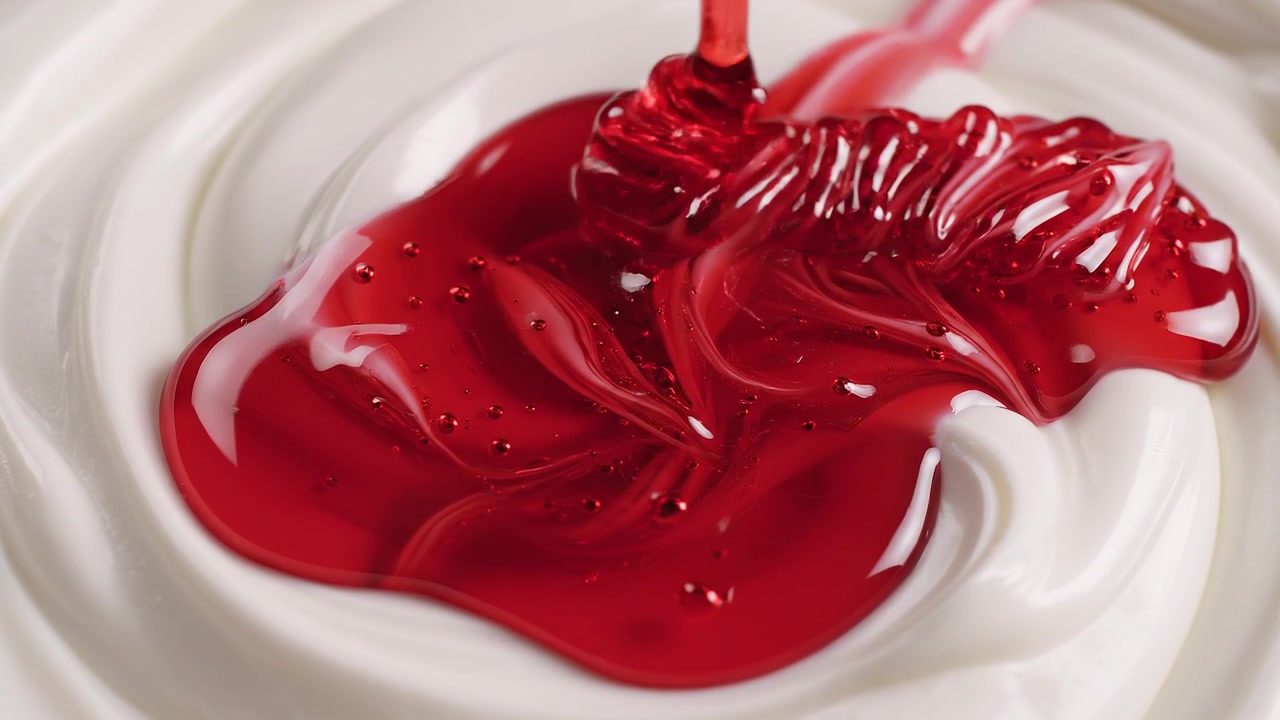 Vibrant Red Syrup Drizzling Over Smooth Creamy White Swirls