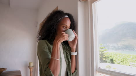 holding coffee, woman looking out window, feeling relaxed at home