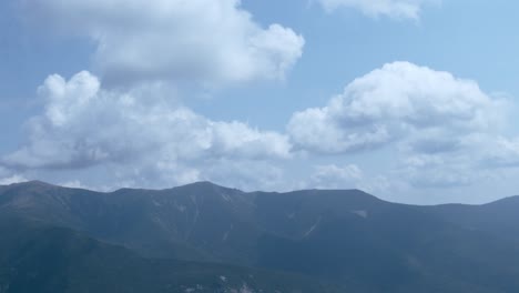 a hazy mountain sits under a cloudy blue sky as the camera tilts down