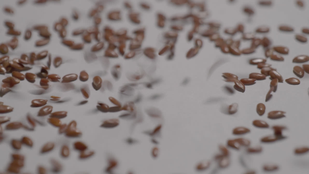 flax seeds falling on white surface and bouncing , 4k, stable shot