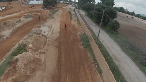 amplio seguimiento aéreo fpv en cámara lenta del piloto de motocross saltando alto, el cielo se refleja en el barro