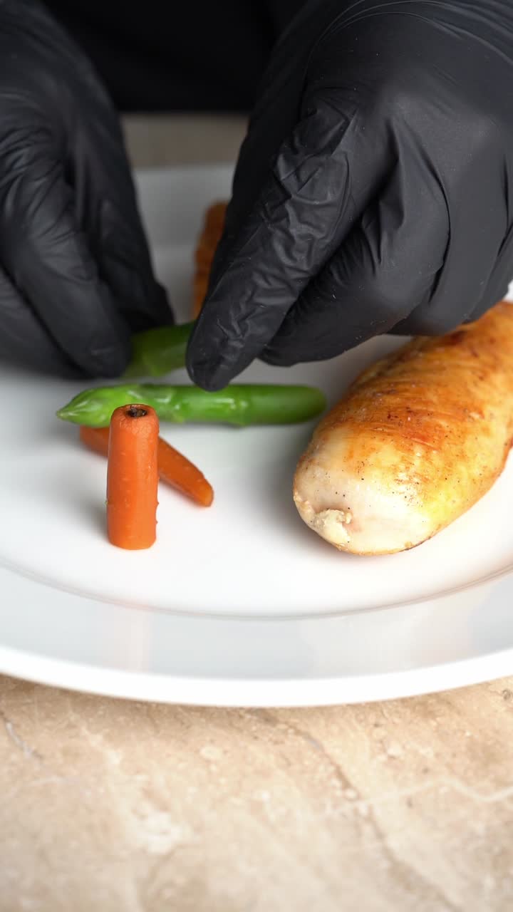 Chief plating roasted chicken piece with carrots and green beans on a plate, close up shot, insert shot