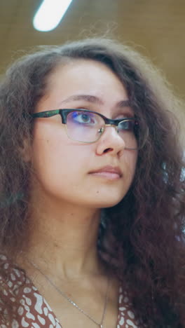 dama con cabello rizado vintage y gafas se centra atentamente en el artículo dentro de su bolsa en el ambiente bullicioso del centro comercial, luces bokeh suaves crean un fondo borroso, atmosférico, con la gente que pasa