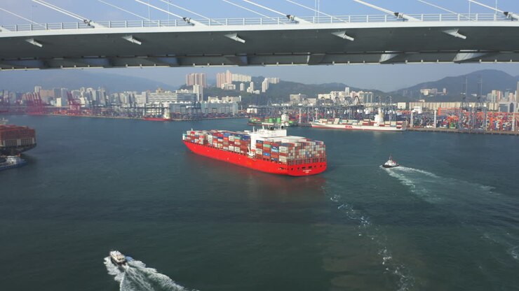 Giant red container vessel approaching berth at the container port in Hong Kong after passing the Stonecutters bridge