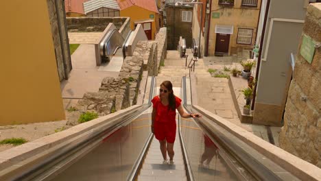 tourist going up escalator in historic site in porto, portugal