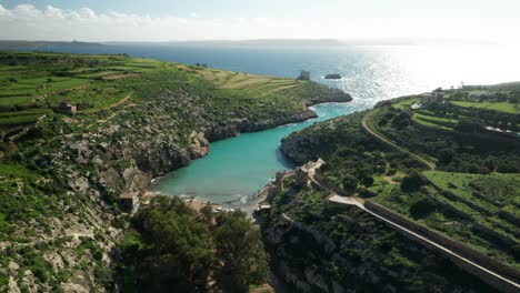 aerial: magrr ix-xini bay surrounded by hills and blue mediterranean sea waves