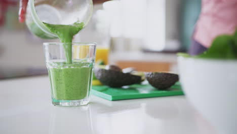 Close-Up-Of-Woman-Pouring-Healthy-Juice-Drink-Into-Glass-From-Blender