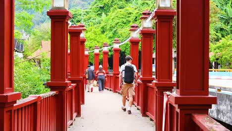 people strolling on a vibrant red bridge