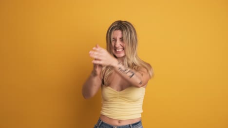 smiling and jumping young woman with raised hands on yellow background