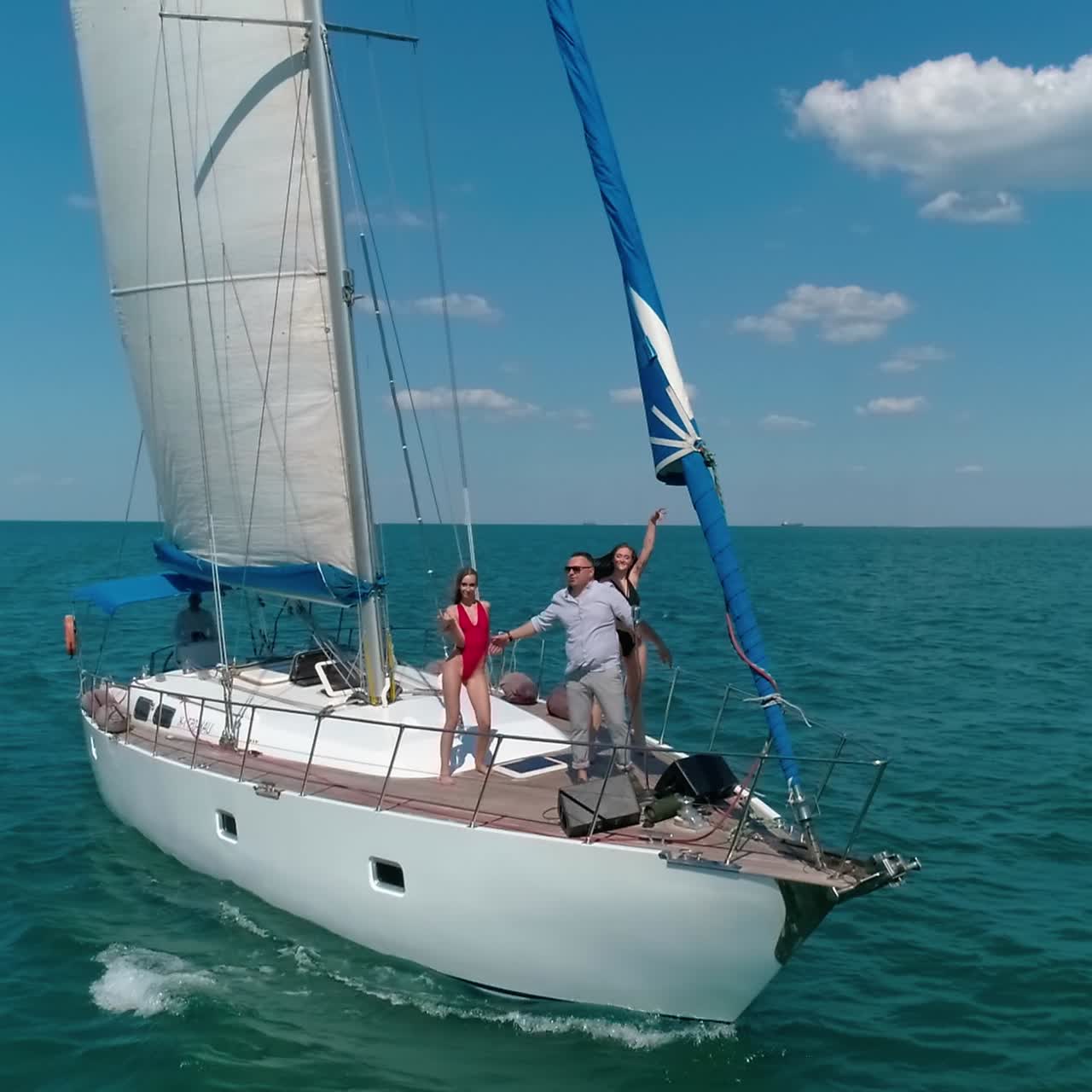 Young group of people have a rest on a yacht. Big yacht riding on the sea
