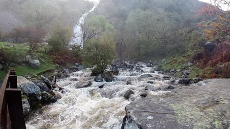 cascada rocosa que fluye a cámara lenta agua del río salpicando en la formación rocosa de la orilla del río brumoso