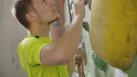 portrait of a climber preparing to climb the wall in the hall to chalk his hands and climb the wall with insurance in slow motion.