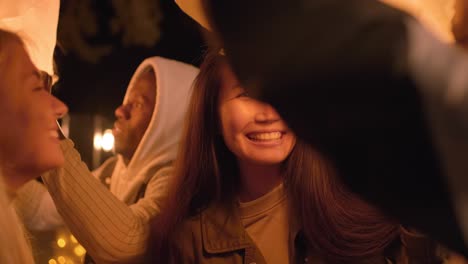 group of intercultural friends making chinese sky lanterns