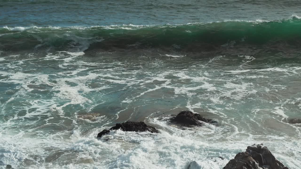 poderosas olas rompiendo sobre rocas en cámara lenta