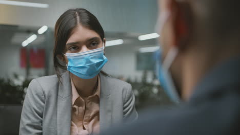 two people in face masks having a professional discussion in an office