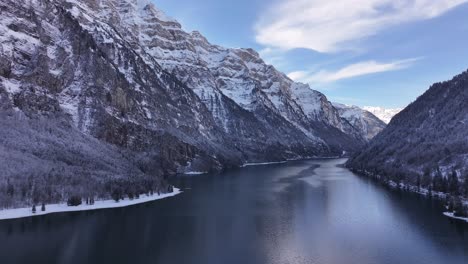 Natural picture frame in Switzerland featuring the completely frozen Lake Klöntalersee, surrounded by stunning alpine scenery.