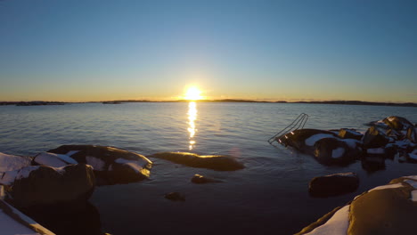 4k wide shot of a beautiful sunset close to a rocky shore with a metal stairs in gothenburg, sweden