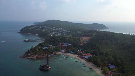 estado de ánimo matutino vista aérea dramática rampa de velocidad de vuelo de una isla tropical con un largo muelle de madera que conduce a un restaurante flotante, rodeado de aguas turquesas y exuberante bosque tropical verde