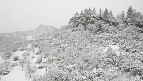 aerial view of drone approaching a rocky outcropping during a winter snow storm