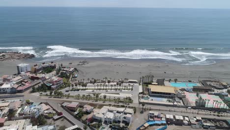 a stunning aerial shot of a coastal town, with waves crashing on a sandy beach. ideal for travel, real estate, and tourism promotions. mollendo, arequipa, peru.