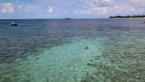 tourist swimming and boat sailing at blue waterscape of bali sea in indonesia