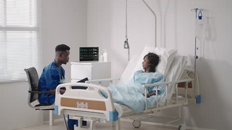 an african male doctor interviews a patient lying in a hospital bed with an oxygen mask. a black woman lying in a hospital bed describes the symptoms to the doctor