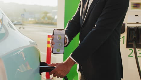 hombre cargando un vehículo eléctrico en una estación de carga