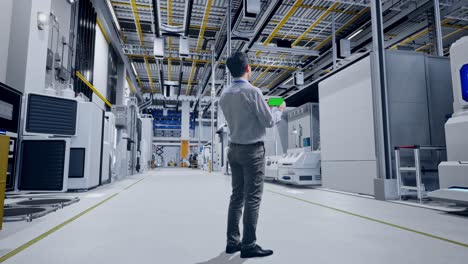 vista trasera completa del cuerpo de un trabajador profesional masculino asiático de pie con un teléfono inteligente de pantalla verde en la digitalización de la fábrica