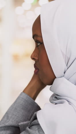 positive african-american lady adjusts new hijab standing near glass display in shopping center closeup. muslim woman buys accessories for everyday life