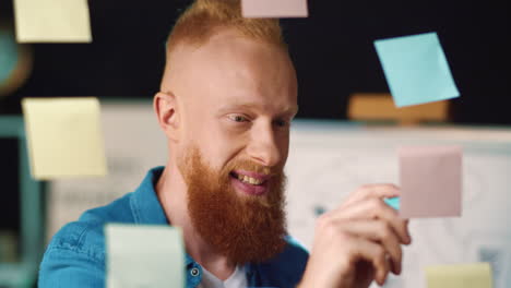 joyful businessman choosing ideas on sticker board. guy working with stickers