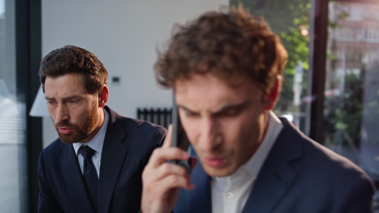 Uomo d'affari preoccupato che chiama con uno smartphone a causa di un problema di lavoro, primo piano nell'atrio di un ufficio
