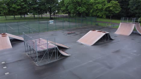 aerial view flying low across fenced skate park ramp in empty closed playground