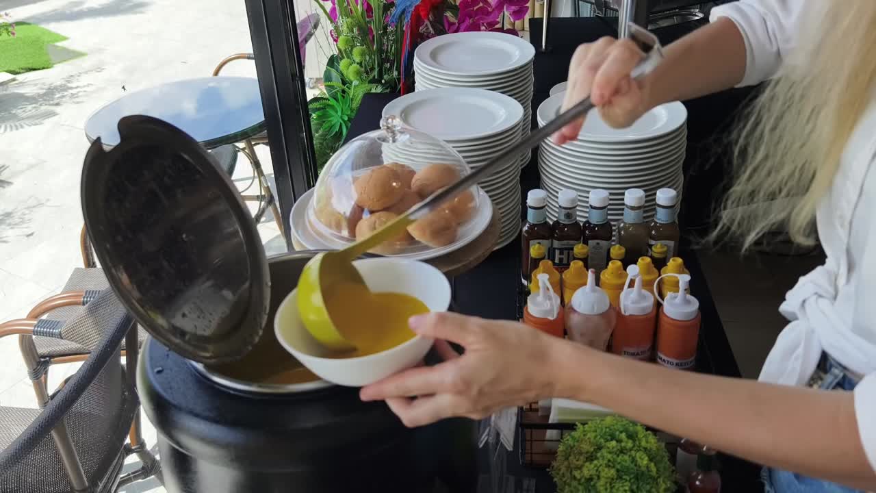 뷔페 스타일 의 식당 에서 수프 를 제공 하는 여자