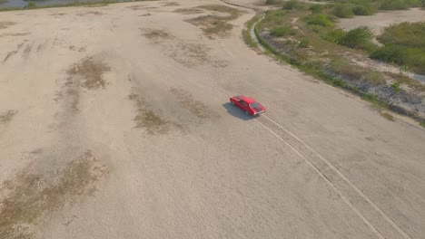 vista de pájaro de un viejo muscle car americano en un camino de tierra durante una puesta de sol