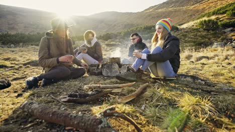 young people preparing meal over fire in mountains
