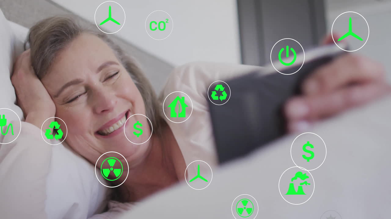 woman lying in bed using tablet, with animated sustainability and energy icons floating above