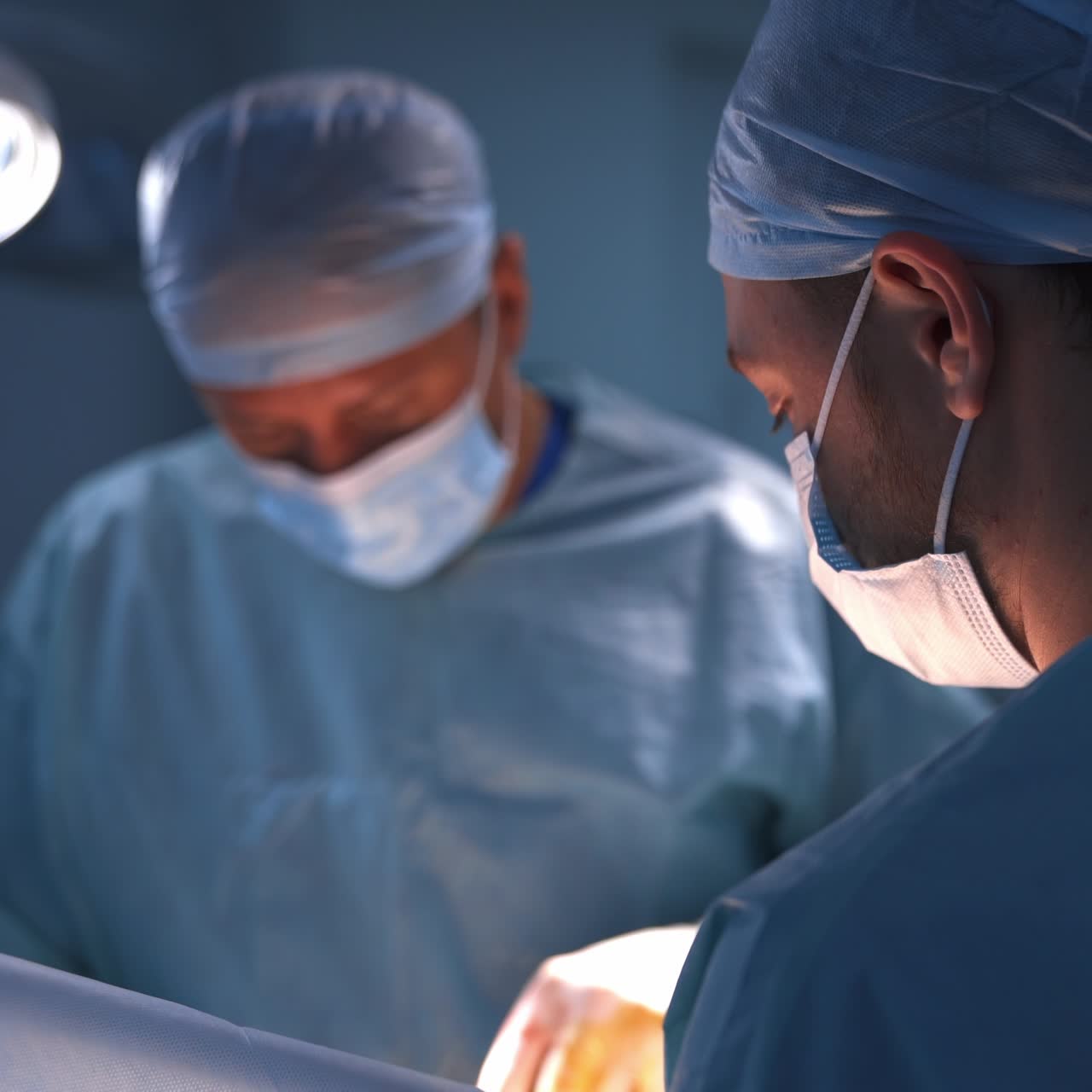 Chirurgo plastico professionista che utilizza uno strumento durante un'operazione. Medico di sesso maschile assiste in primo piano. Sfondo sfocato