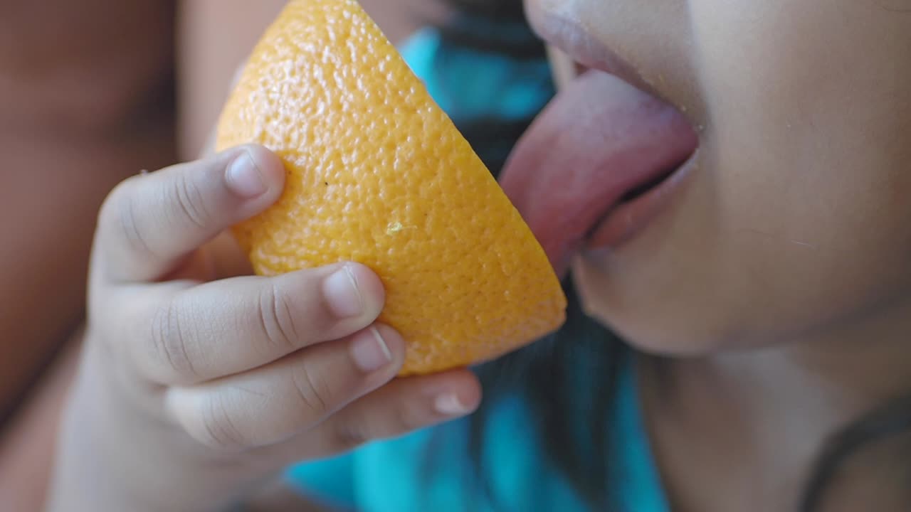 una niña comiendo una naranja
