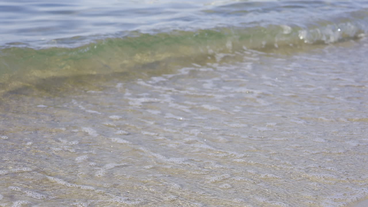 Close up of waves crashing on the beach in daylight