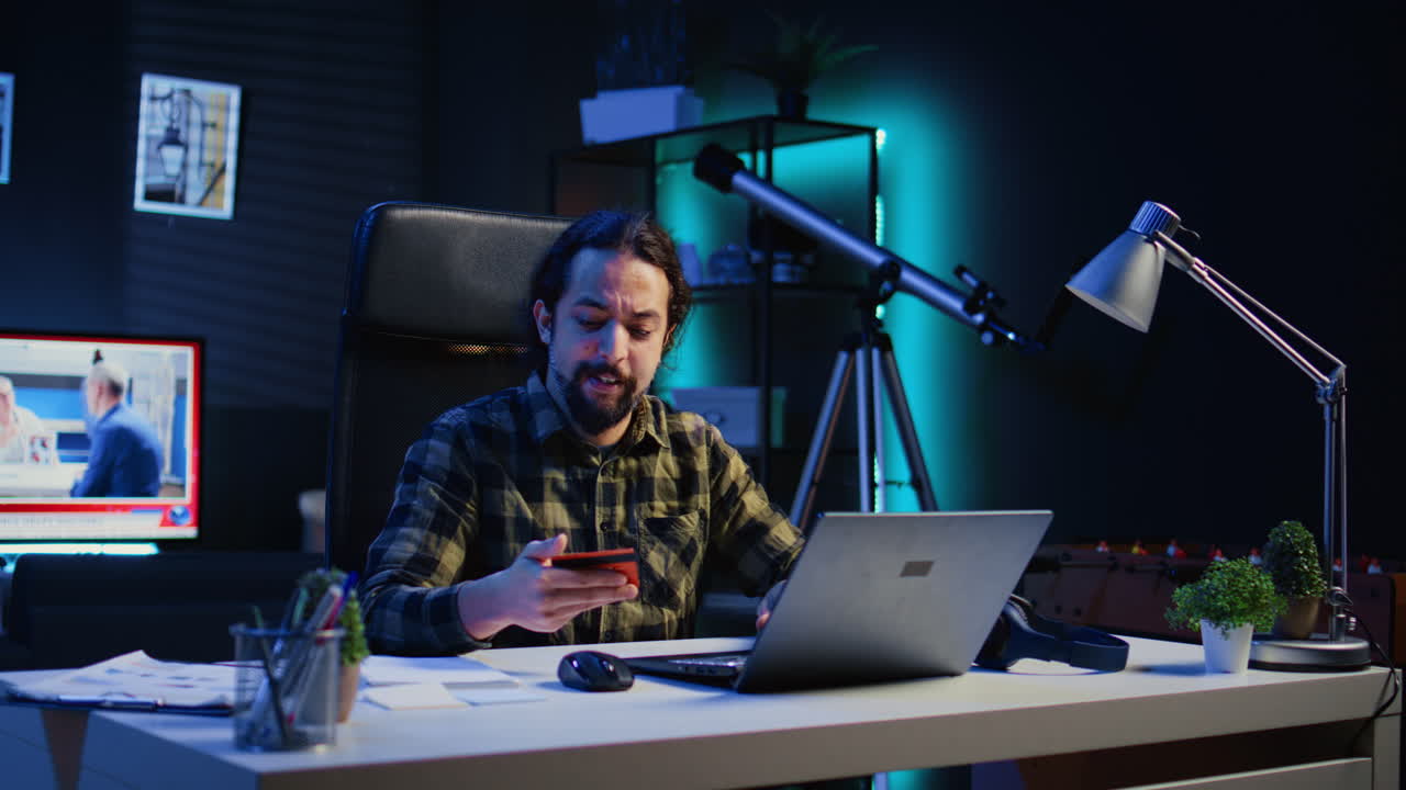 Happy man doing internet shopping, typing credit card information on laptop